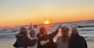 Four women raising a glass to the sunset over Lake Michigan.